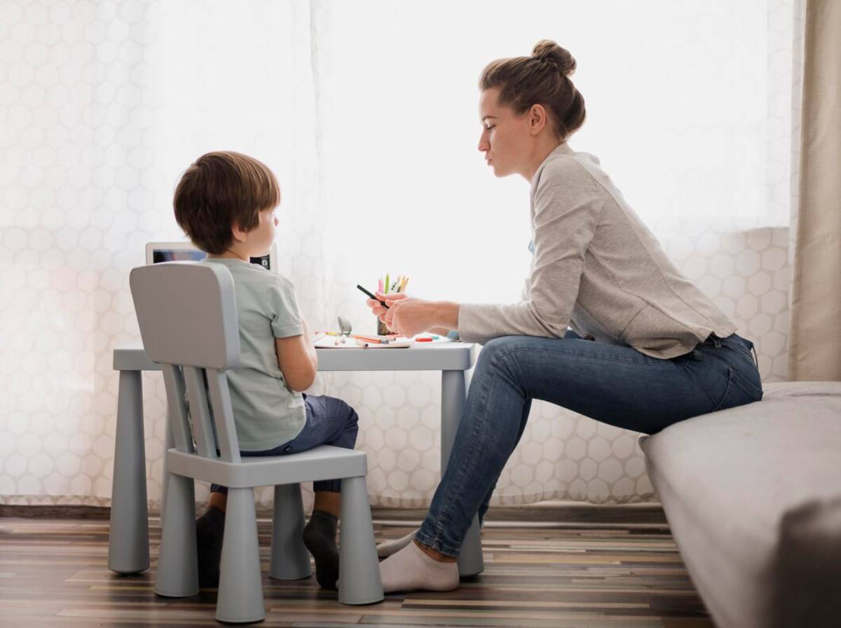 A woman and a child are seated together at a table, engaged in conversation or activity.