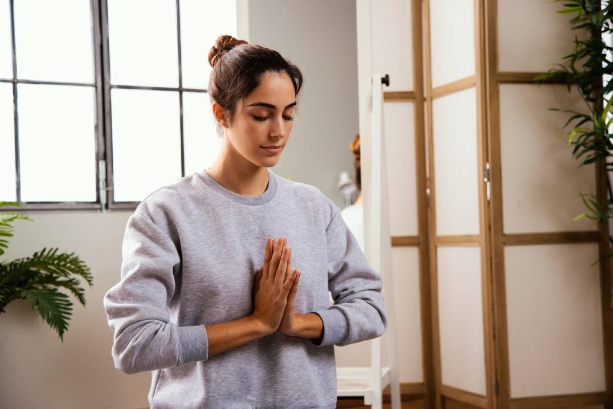 A woman practicing yoga poses in her cozy living room, surrounded by natural light and indoor plants.
