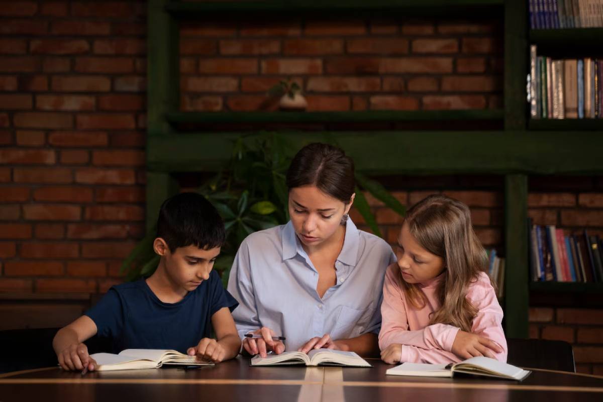 A woman and two children sit at a table, engaged with various books spread out before them.