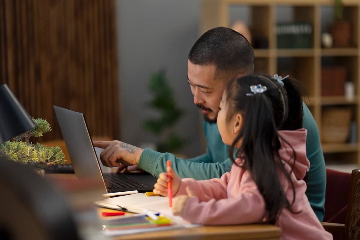  A man and a young girl collaborate on a laptop, focused on the screen and engaged in their task.
