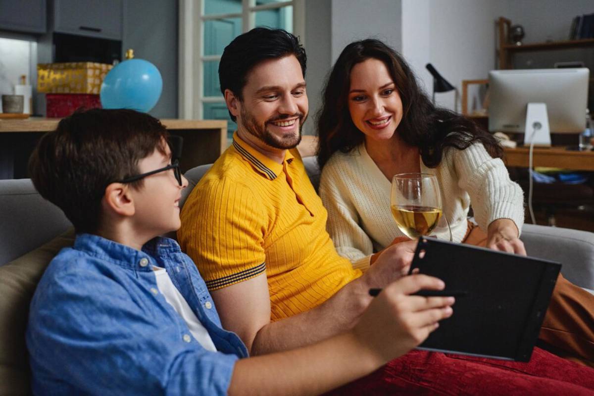 Family of three enjoying time together with digital tablet on a couch.