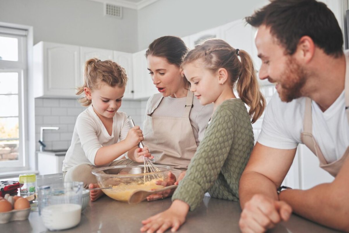 Family of four happily baking together in a modern kitchen.