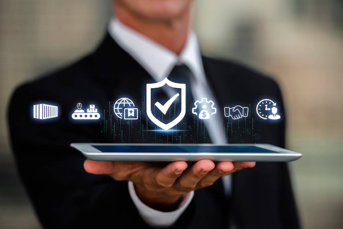 A businessman in a suit holds a tablet displaying digital icons for security, logistics, and communication.
