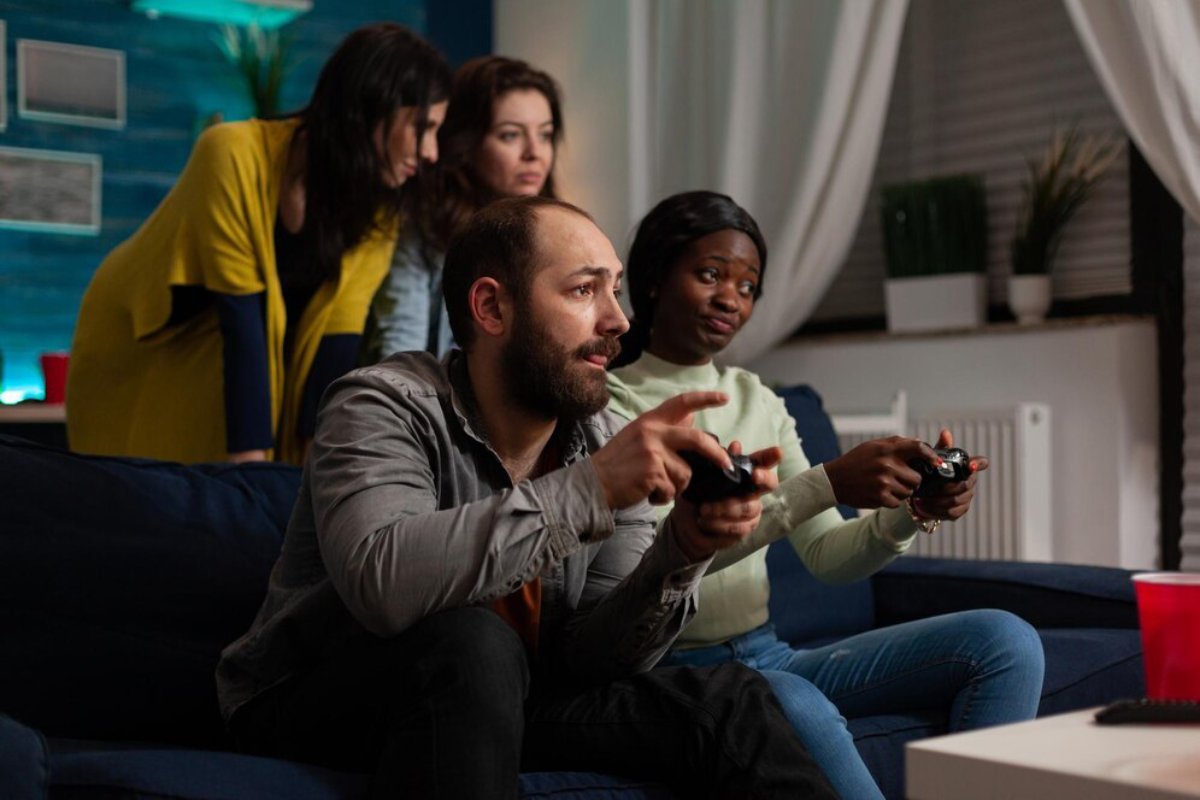 Three women and a man playing video games intently in a home living room.
