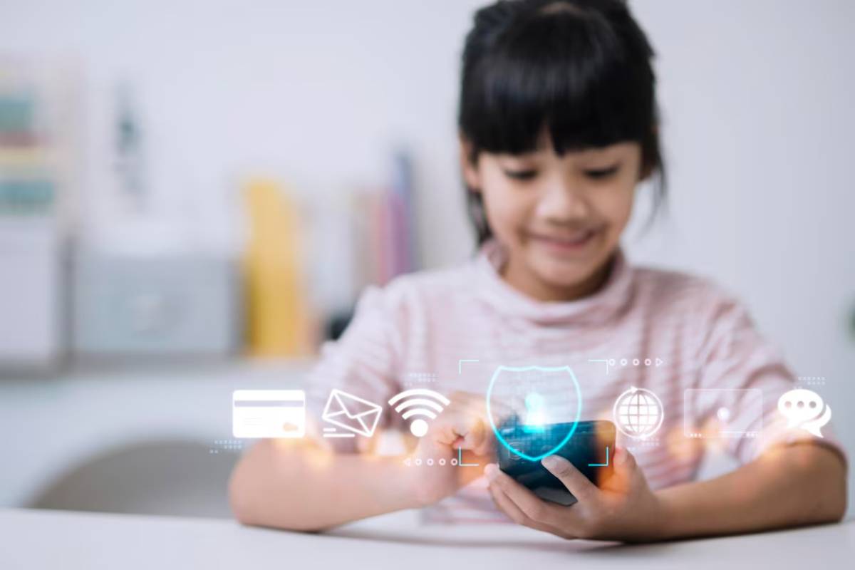 A child sits at a table, holding a smartphone, with digital icons representing communication and online security floating nearby.